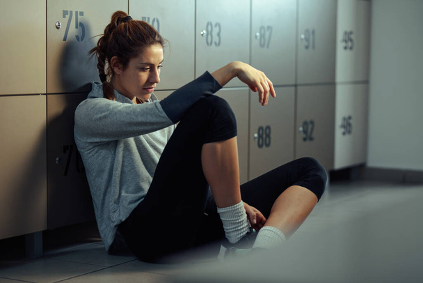 Young sportswoman resting in gym's dressing room before sports training.  - Foto, imagen