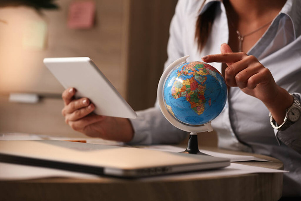 Unrecognizable businesswoman examining globe while using touchpad in the office.  - Foto, Imagem