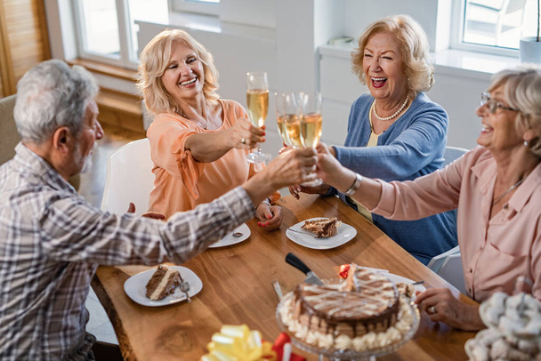 Cheerful seniors toasting with champagne and having fun on a birthday party at home.  - Fotó, kép