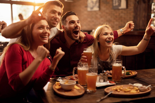 Group of excited fans having fun while watching sports match and cheering for their team in a pub.  - Zdjęcie, obraz