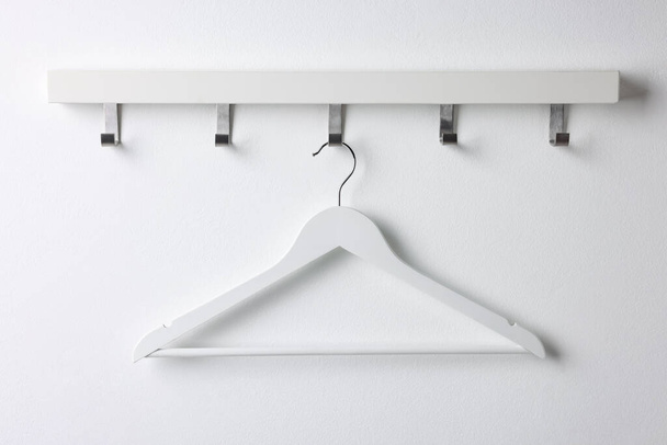 Rack with empty clothes hanger on white wall - Φωτογραφία, εικόνα