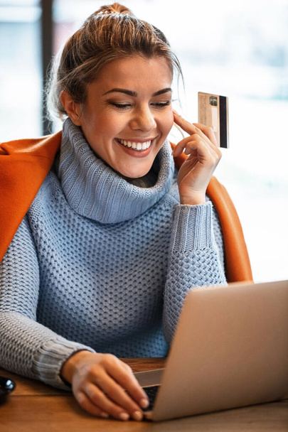 Νεαρή ευτυχισμένη επιχειρηματίας e-banking σε φορητό υπολογιστή, ενώ χαλαρώνοντας σε ένα καφέ,  - Φωτογραφία, εικόνα