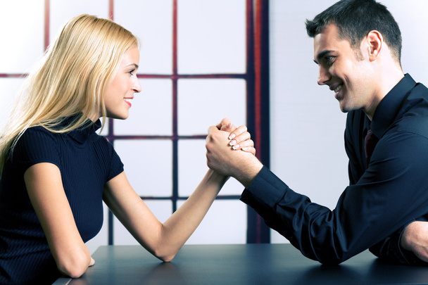 Young happy couple or business people fighting in arm-wrestling - Foto, imagen