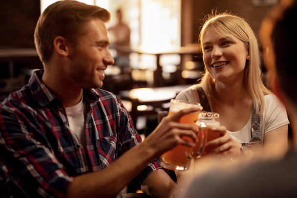 Young happy couple toasting with beer and having fun in a bar.  - Fotoğraf, Görsel