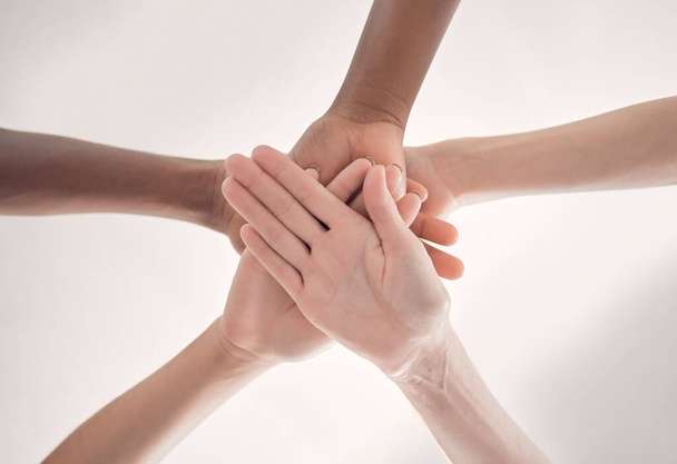 Group of diverse businesspeople piling their hands together in an office at work. Business professionals having fun standing with their hands stacked for support and unity from below. - Foto, Bild