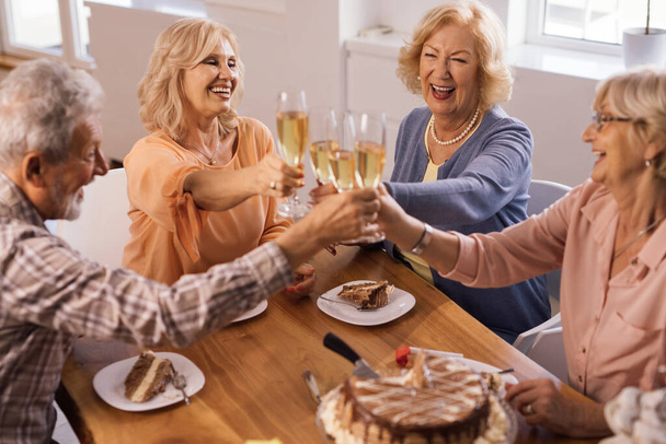 Group of cheerful senior people raising a glass and toasting on a Birthday party at home.  - Foto, Imagen