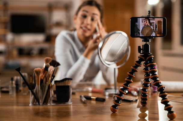 Close-up of woman recording make-up tutorial while applying eyeshadow at home.  - Zdjęcie, obraz