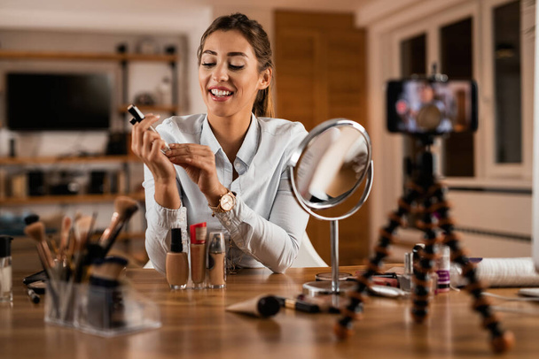 Happy make-up artist recording video tutorial about beauty products for her vlog at home.  - Foto, imagen