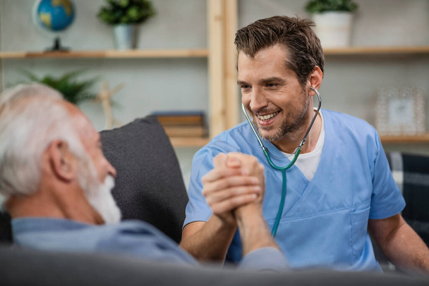 Happy healthcare worker greeting his mature patient while being in a home visit.  - Foto, immagini