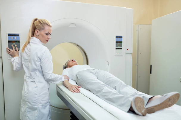Жінка-радіолог контролює зрілого пацієнта, який проходить процедуру КТ в лікарні
. - Фото, зображення