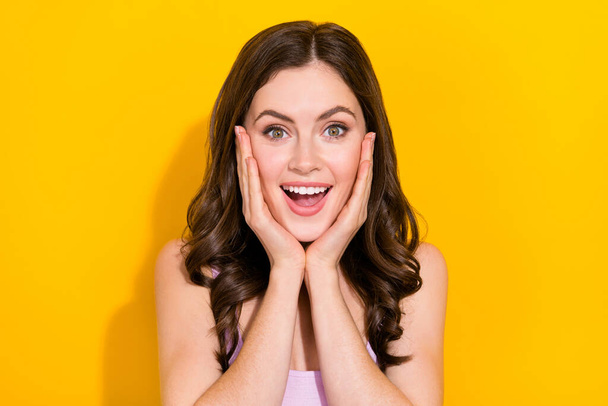 Portrait of impressed pretty girl arms cheeks open mouth look camera isolated on yellow color background. - Foto, Imagem