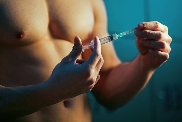Close up of male bodybuilder using recreational drugs before in locker room before sports training.  - Photo, image