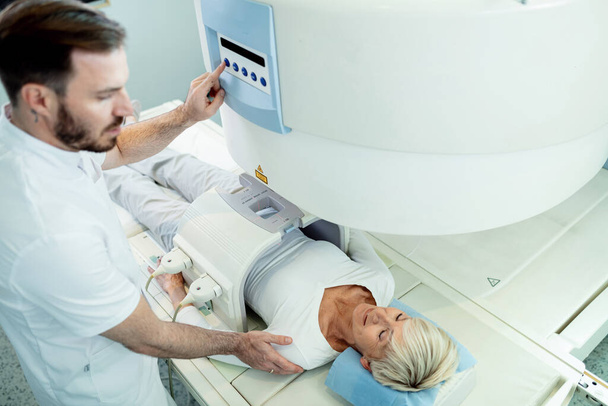 Вид зверху на зрілу жінку-пацієнта, що отримує пухлину МРТ сканування в клініці
.  - Фото, зображення