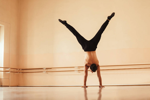 Rear view of a dancer exercising in a studio and doing a handstand. Copy space. - 写真・画像
