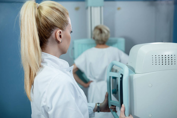Жіночий технік приймає медичний рентген пацієнта в клініці
.  - Фото, зображення