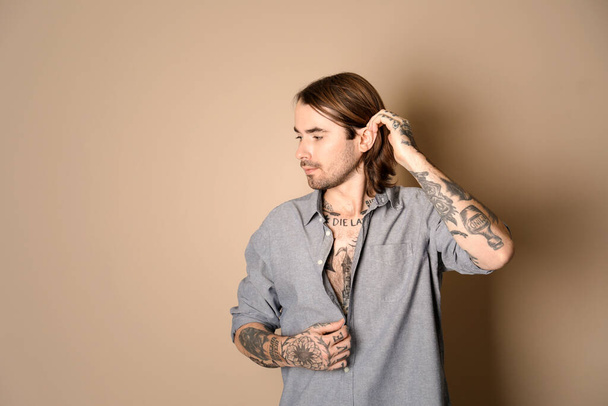 Young man with tattoos on body against beige background. Space for text - Foto, afbeelding