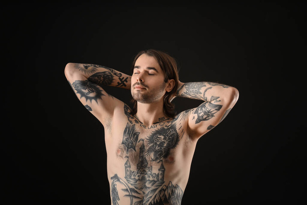 Young man with tattoos on body against black background - Foto, Bild