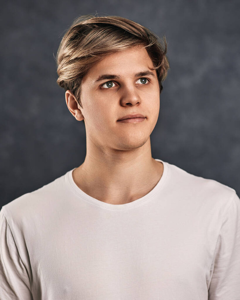 portrait of calm young handsome guy in white shirt on gray background. - Фото, зображення
