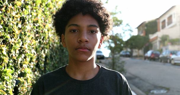 Mixed race kid walking outside in sidewalk street. Young boy walks outdoors - 写真・画像