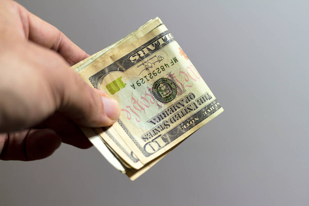 Male hand holding a dollars banknotes. Selective focus of a man with American money closeup. - Valokuva, kuva