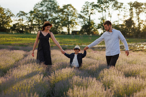 Šťastná rodina kráčí po levandulovém poli a drží se za ruce. - Fotografie, Obrázek