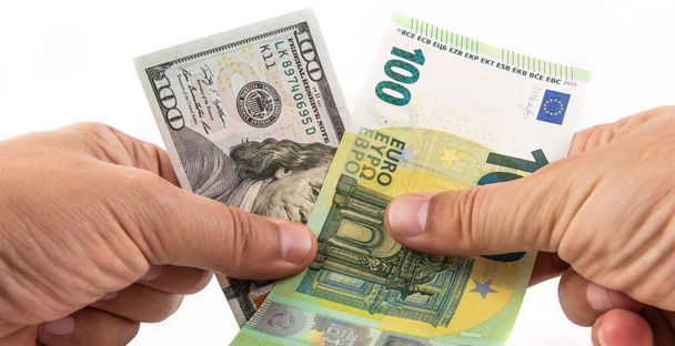Bankbiljetten in coupures van 100 Amerikaanse dollar en 100 euro in mannelijke handen op een witte achtergrond - Foto, afbeelding