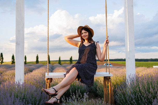 Pretty woman posing on a swing in a field - Фото, зображення