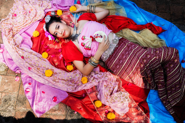Belle femme thaïlandaise portant des vêtements traditionnels thaïlandais s'allongent sur de la soie de différentes couleurs. - Photo, image