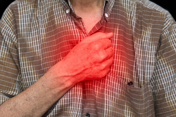 Asian elder man suffering from central chest pain. Chest pain can be caused by heart attack, myocardial infarct or ischemia, myocarditis, pneumonia, oesophagitis, stress, etc,. - Fotografie, Obrázek
