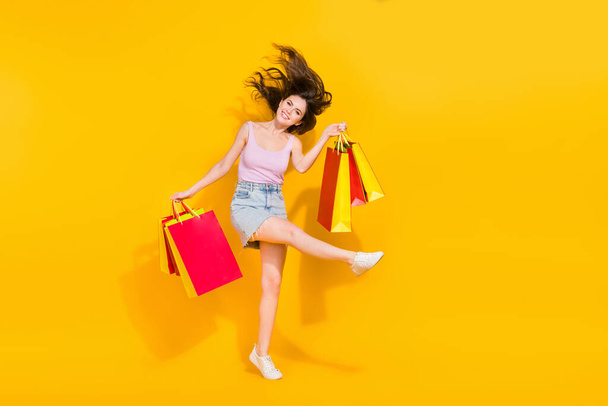 Full length portrait of carefree positive lady hold packages have good mood isolated on yellow color background. - Photo, Image
