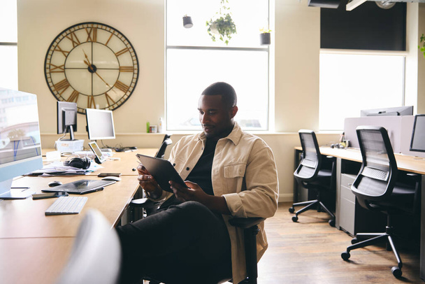 Молодой мужчина реклама маркетинг или дизайн Творческая работа на цифровой планшет в современном офисе, сидя за столом - Фото, изображение