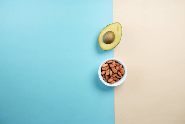 top view of slice of avocado and almond nuts on color background , - Foto, Bild