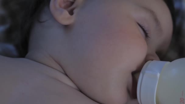 Портрет сплячої маленької дитини з пляшкою в роті. Дитина їсть уві сні. Дитина п'є молоко з пляшки і спить. Високоякісні 4k кадри
 - Кадри, відео