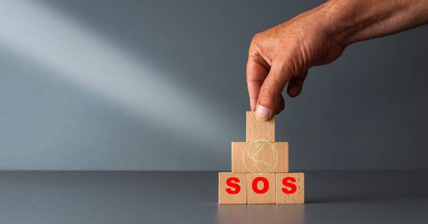 save the planet concept ,wooden blocks with green planet and SOS in red , with grey background , room for your text . - 写真・画像