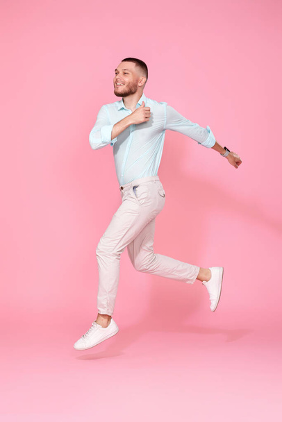 молодий чоловік в літньому одязі стрибає ізольовано на рожевому фоні. Повна довжина
 - Фото, зображення