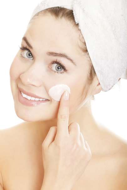 Beautiful woman applying moisturizer cream on face. - 写真・画像