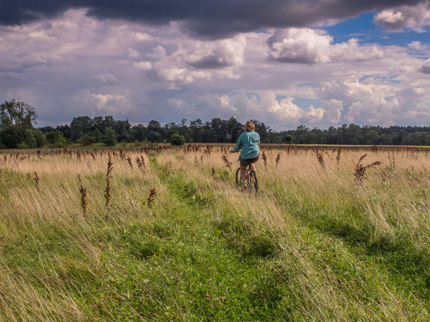 Woman on a bicycle during a bicycle tour, embankment  over the Bug river,  Podlasie, Podlachia - Foto, Imagen