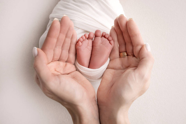 Childrens legs in the hands of mother, father, parents. Feet of a tiny newborn close up. Mom and her child. Happy family concept. Beautiful concept image of motherhood stock photo. - Fotó, kép