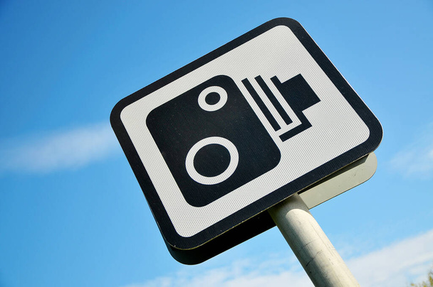 Angled view of Speed Camera Signpost against a blue sky. - Фото, изображение