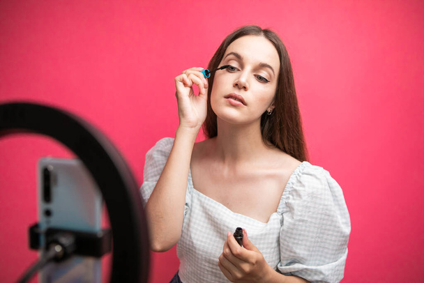 Beauty blogger recording makeup tutorial on pink background. High quality photo - Foto, afbeelding