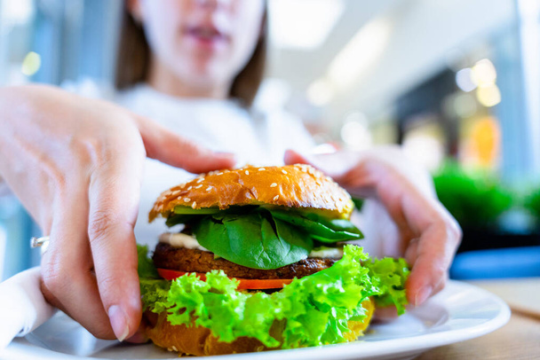 Vegan burger υγιεινό χορτοφαγικό χάμπουργκερ. Σαλάτα, αβοκάντο, λαχανικά σε σάντουιτς λαχανικών τρώγοντας χαριτωμένη γυναίκα. Χορτοφαγικά χάμπουργκερ υγιεινή διατροφή - Φωτογραφία, εικόνα