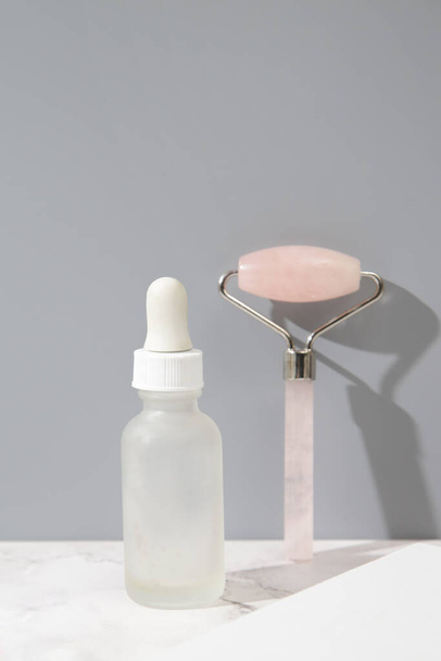 Rose quartz facial roller and face serum for anti aging facial massage. Skin care luxury beauty tool. - Photo, Image
