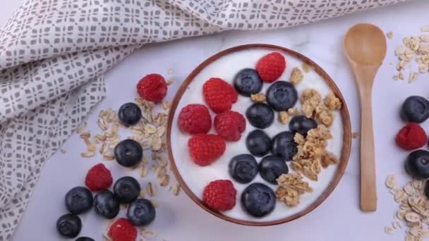 A portion of yogurt with blueberry raspberry and oat flakes in a wooden bowl ready to be served. Healthy food for dieting concept. Fruit muesli with yogurt. Dolly shot 4k - Filmagem, Vídeo