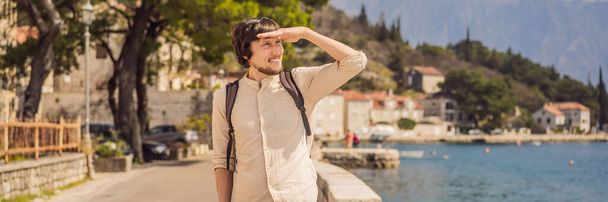 BANNER, LONG FORMAT Man tourist enjoying Colorful street in Old town of Perast on a sunny day, Montenegro. Travel to Montenegro concept. Scenic panorama view of the historic town of Perast at famous - Foto, afbeelding