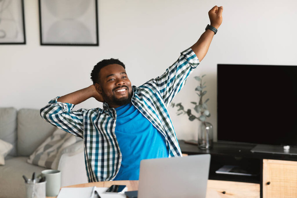 Successful Freelance Career. Relaxed Black Man Stretching Hands After Successful Work Day Sitting At Laptop Computer At Home. Remote Job, Internet Business And Technology Concept - Valokuva, kuva