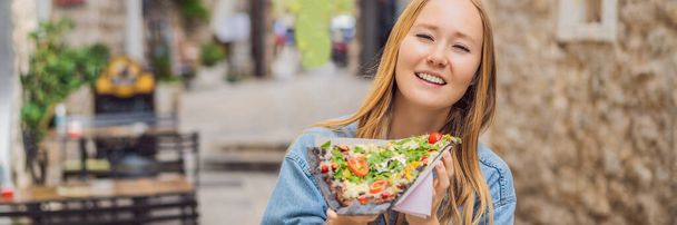 BANNER, LONG FORMAT Young woman tourist eating traditional pizza in the old town of Budva. Travel to Montenegro concept. - Foto, Bild
