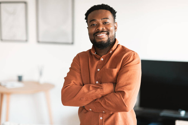 Cheerful African American Millennial Man Posing Crossing Hands Standing At Home. Handsome Bearded Guy Smiling To Camera. Successful Male, Real Estate Ownership Concept - Foto, Imagen