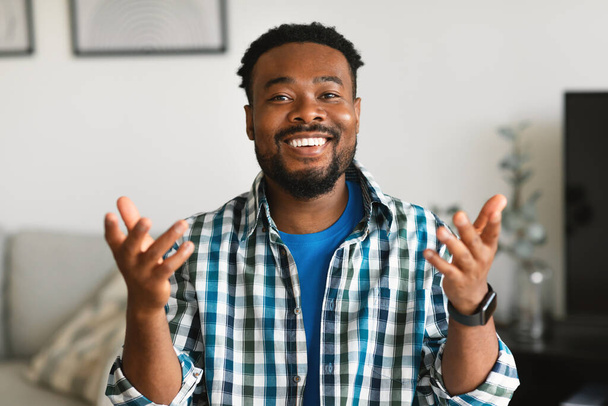 Cheerful Black Man Talking Looking At Camera Having Video Call Sitting At Home. Millennial Male Communicating Distantly Online Indoors. Remote Communication Concept - 写真・画像