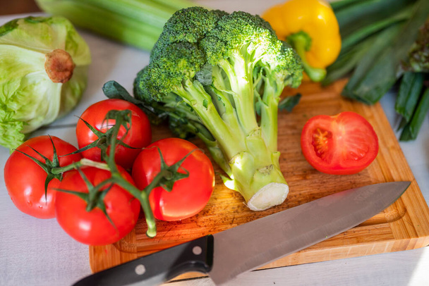 fresh vegetables for iceberg salad with paprika with cabbage broccoli tomatoes and celery on a wooden board - 写真・画像