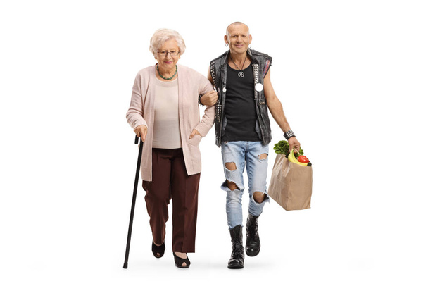 Man holding a senior woman under arm and carrying her grocery bag isolated on white background - Zdjęcie, obraz
